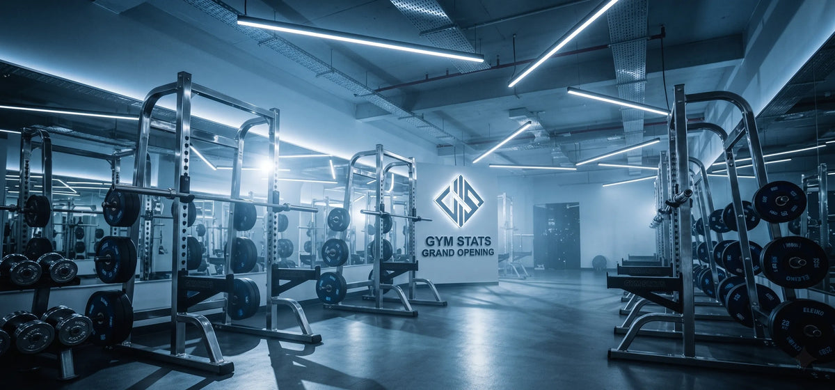Modern och exklusiv gymmiljö med skivstänger, hantlar och Gym Stats logotyp på väggen i professionellt blått ljus.